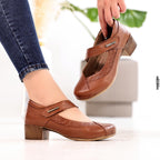 Brown shoes with 'Beautiful Comfort' branding worn by a person, with a blurred background.