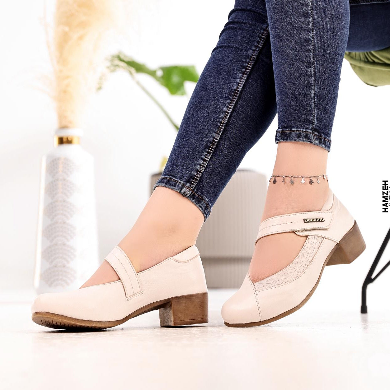 White shoes worn with blue jeans on a blurred indoor background, featuring the 'B Beautiful Comfort' brand.