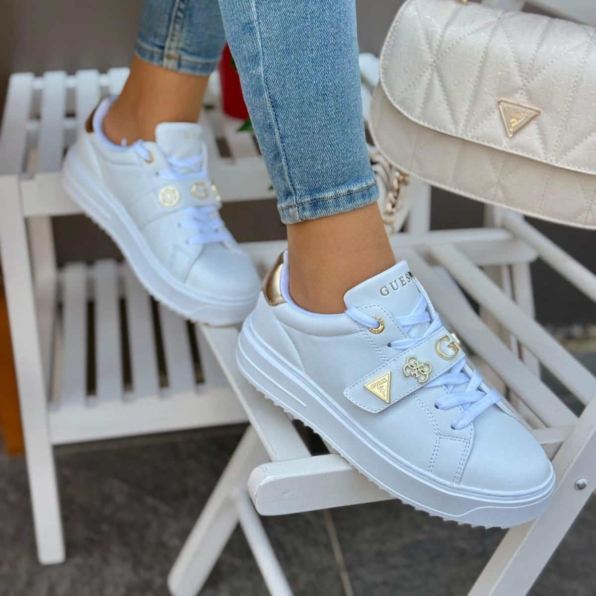 Light blue sneakers with gold accents worn by a person sitting on a chair.