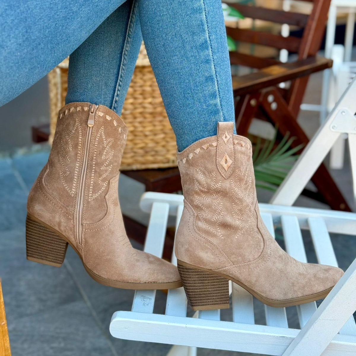 Tan cowboy boots worn with blue jeans on a chair.