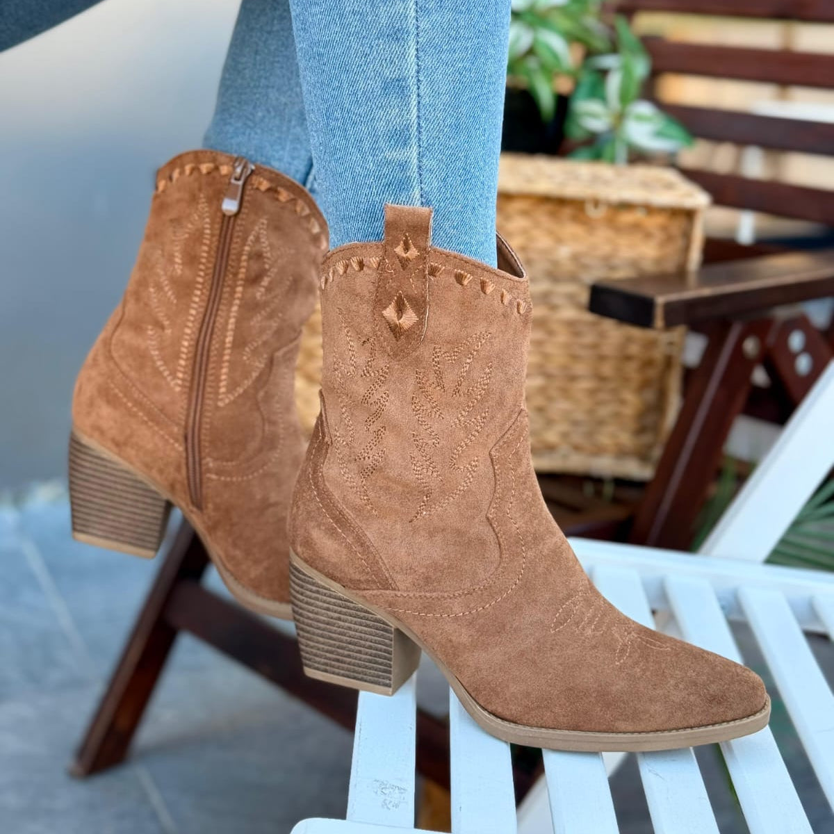 Brown suede boots worn with light blue jeans on a chair.