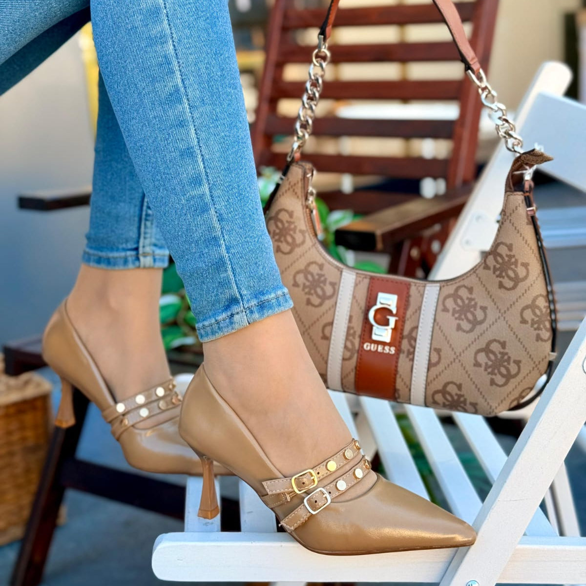 Person wearing beige high-heeled shoes and holding a patterned handbag.