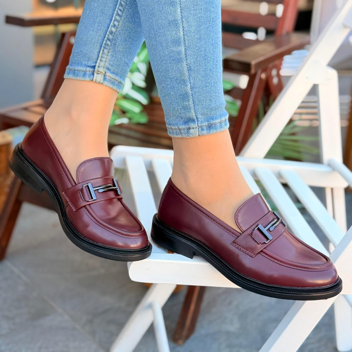 burgundy loafers worn with light blue jeans on a chair.