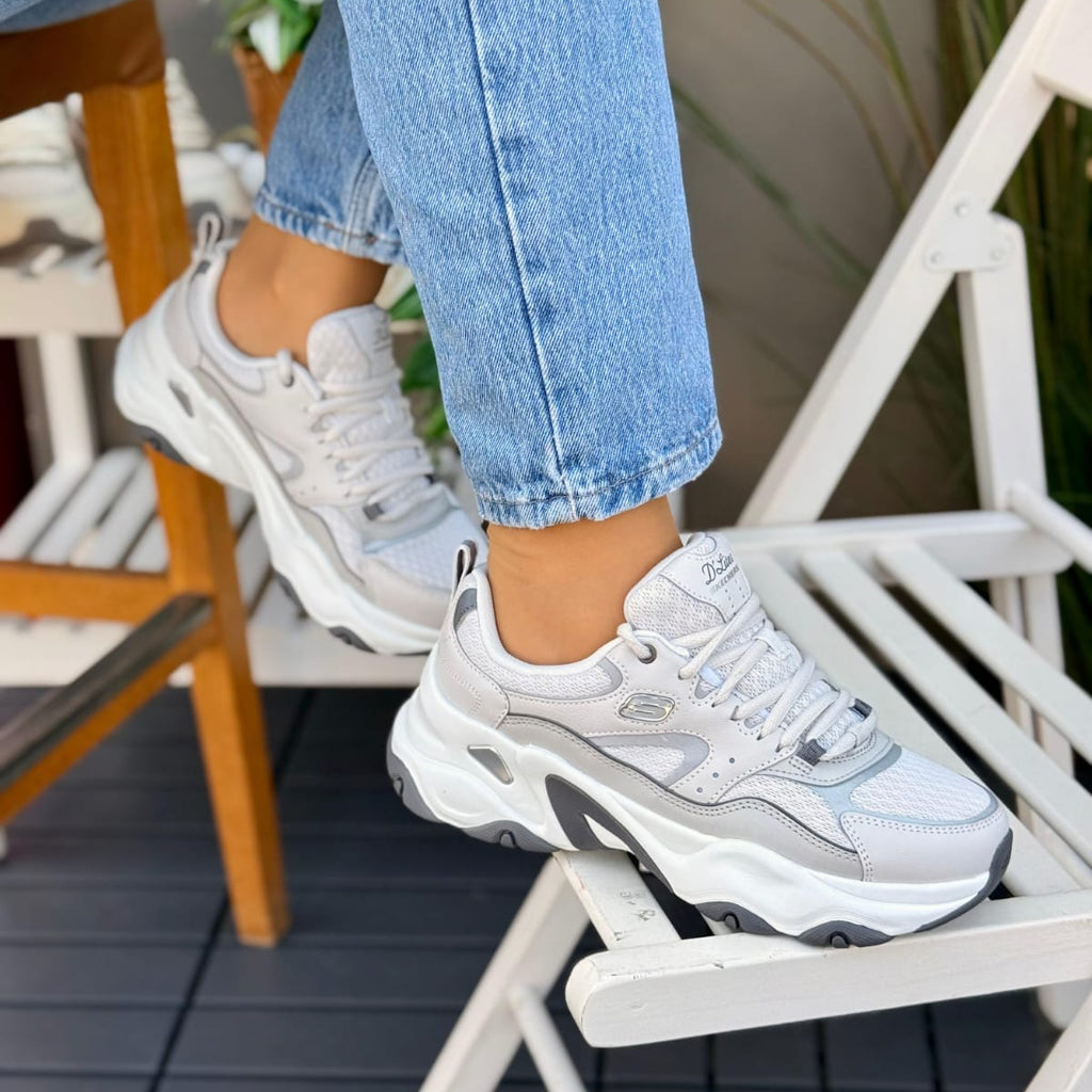 Woman wearing Skechers D'Lites 5.0 Team Neutral grey chunky sneakers with white and grey sole.