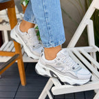 Woman wearing Skechers D'Lites 5.0 Team Neutral grey chunky sneakers with white and grey sole.