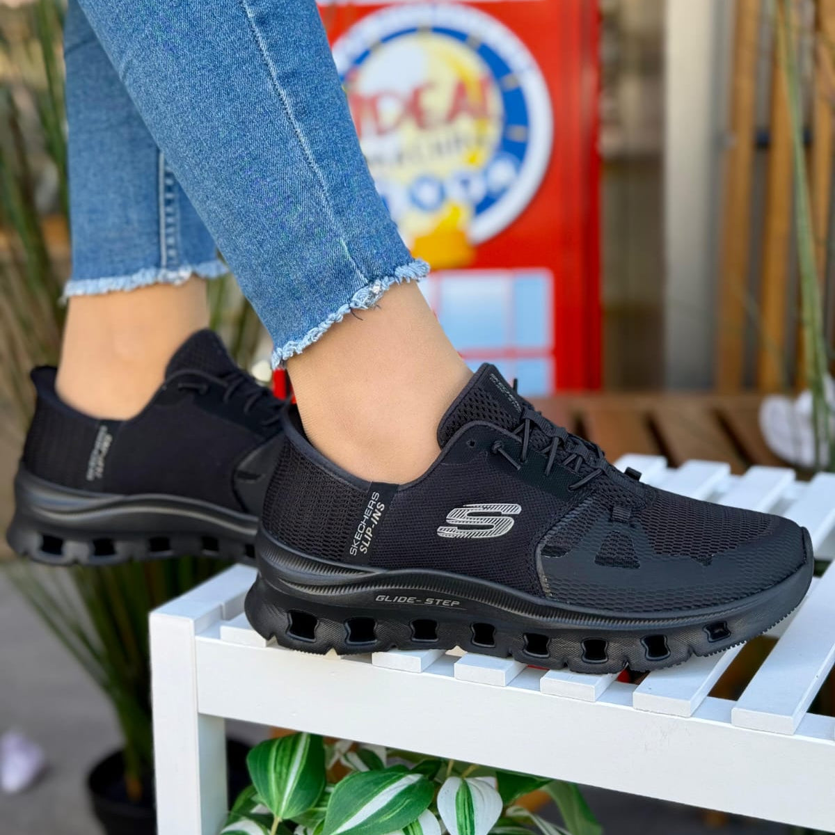 Woman wearing Skechers Glide-Step Pro black slip-ins with geometric sole design sitting outdoors.