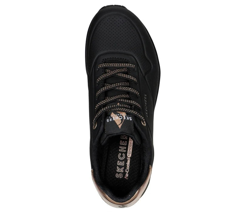 Top view of Skechers Uno Shimmer Away women’s black sneakers showing gold metallic details and Air-Cooled Memory Foam insole.