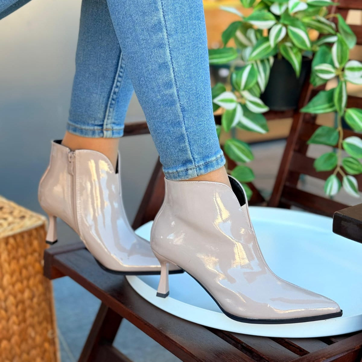 White high-heeled ankle boots worn with blue jeans in an indoor setting.