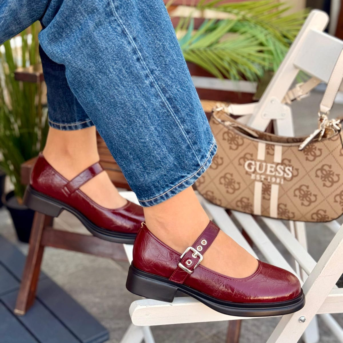 Person wearing burgundy shoes with a brown handbag in the background